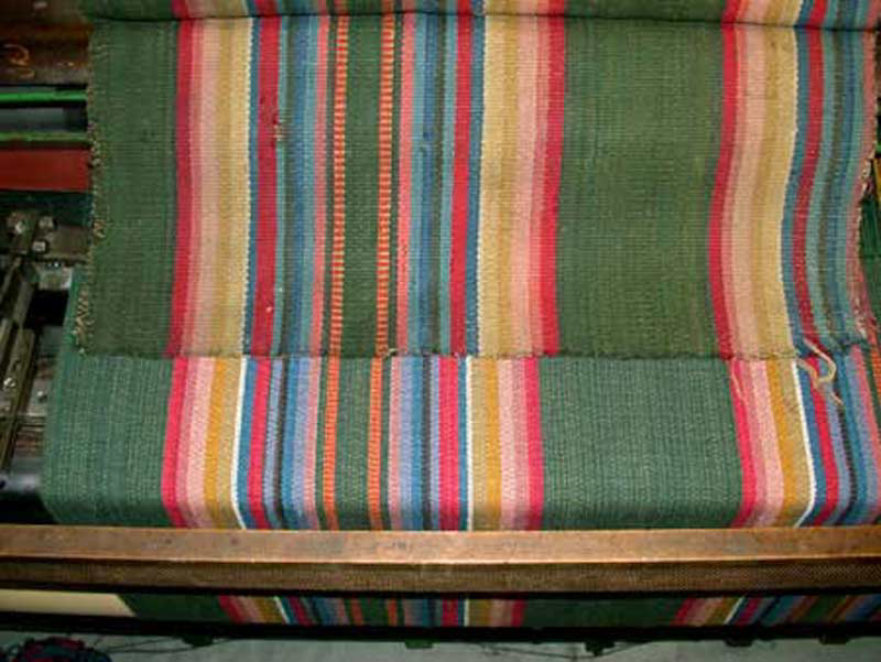 We can produce very close reproductions of historic carpet. This
image shows a surviving original fragment (above) and our reproduction (below) as it is being woven on the loom. We custom dyed the yarns and matched the pattern exactly.